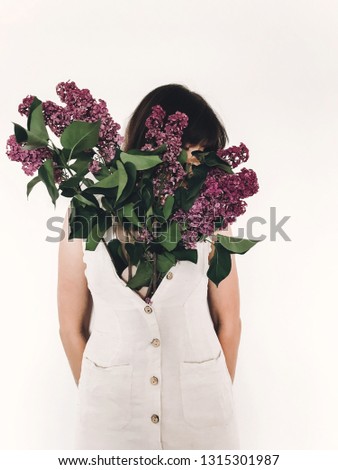 Purple lilac flowers growing from girl in rustic linen dress on white background. Hello spring. Happy Mothers day. Lilac bouquet in woman dress. International womens day. Creative photo