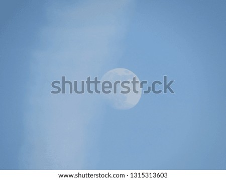 Photo of the moon against the blue sky, craters on the moon