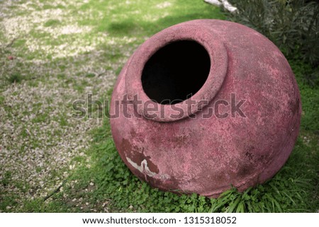 Purple big vintage clay vase on green field, close up