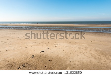 Picture of the beach on a sunny day in spring and in the distance the silhouette of a lone rider on a horse.