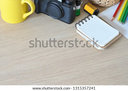 Creative workspace camera and office supplies on wood desk.