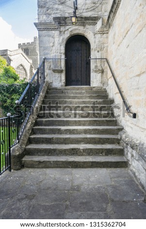 Ancient stone steps leading up to a wooden door with a church in the background
