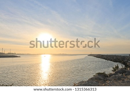 evening sky background in the rocky coastline 
red sunrise over the sea, rich in dark clouds, rays of light with waves slowly rushing across the rocks of Rayong beach in Thailand