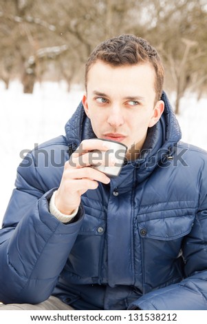 Man warming up with hot tea in cold winter time sitting