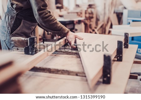 Woodwork and furniture making concept. Carpenter in the workshop marks out and assembles parts of the furniture cabinet close up Royalty-Free Stock Photo #1315399190