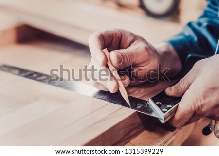 Woodwork and furniture making concept. Carpenter in the workshop marks out the details of the furniture cabinet using a setsquare close up Royalty-Free Stock Photo #1315399229