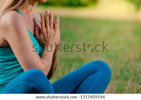 Closeup of young relaxed woman meditating in summer park