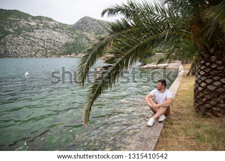 man sitting at seaside with beautiful view. mountains on background. summer time