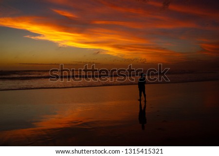 Young man walking outdoors watching the sunset at a beach. Thinking and relaxing concept.