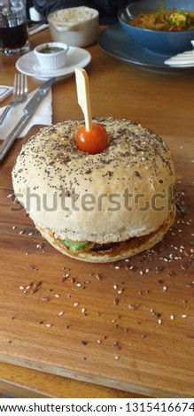 Close-up photo of a delicious burger in restaurant on a wooden table - Stock Image