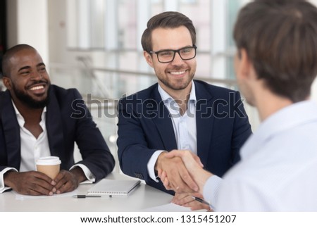 Cheerful successful businessmen meet at boardroom multiracial entrepreneurs starting collaboration negotiations with handshake, make good deal, signing contract, employment and human resources concept Royalty-Free Stock Photo #1315451207