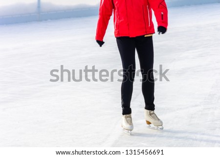 A young slender girl skates and helps beginners