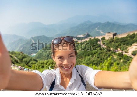 Tourist traveling the world taking travel selfie photo at Badaling Great Wall of China. Beijing attraction. Woman tourist taking picture using mobile phone on Asia vacation.