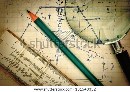 magnifying glass and a slide rule on the old page with the calculations in mechanics Royalty-Free Stock Photo #131548352
