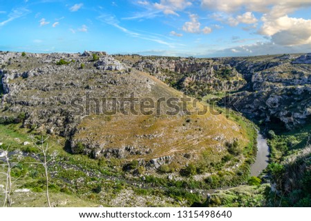 The prehistoric sassi caves, caverns and dwellings are visible in the hillside above the canyon ravine and river in the Basilicata city of Matera, Italy.