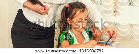 Mother looking how her child daughter drawing a picture