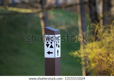 Wooden signpost WC in the park.