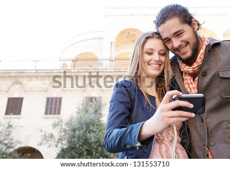 Young couple on vacation using a digital photo camera to take pictures of themselves in a destination city.