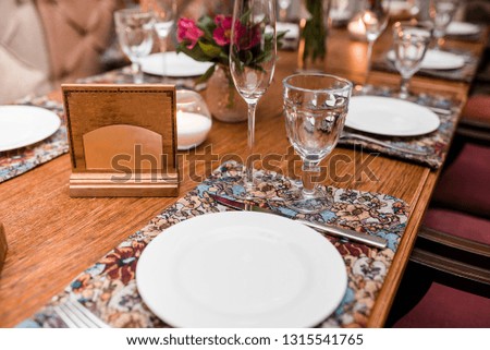Wooden reserved plate on restaurant table with empty dishes and glasses