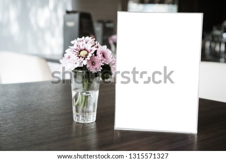 Mock up white Label for blank menu frame in restaurant cafe with plant flower. Stand booklet sheets paper tent card on table cafeteria display your product  background insert  text of customer.