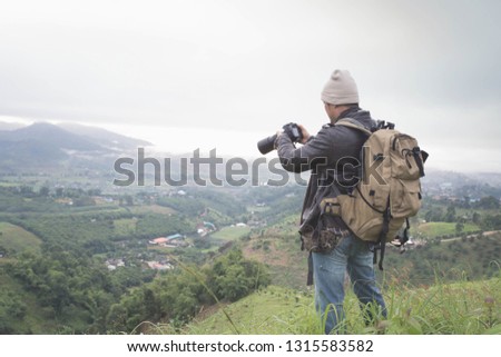 Photographer hand holding camera and standing on top of the mountain  in nature. Travel concept. Vintage tone.