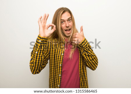 Blond man with long hair and with checkered shirt showing ok sign with and giving a thumb up gesture