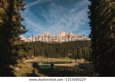 Golden hour view of Lago Di Carezza with reflections of mountains and sky on lake in South Tyrol in Northern Italian Dolomites during the fall. 