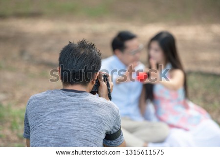 photographer is shooting a pre-wedding album for a married couple. Behind the scenes of camera shooting or video production and film crew team with camera equipment on location.