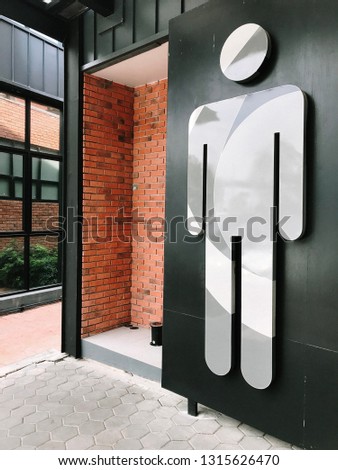 Toilet signs for men on a black wall and brick.