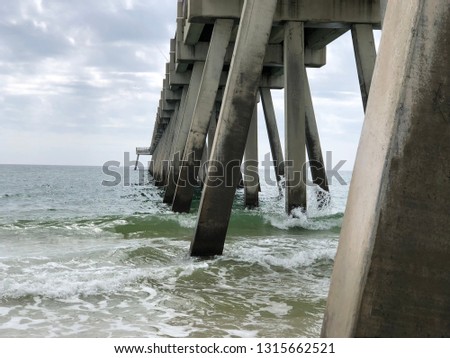 Industrial Fishing Pier scenic views from under the abutments looking at several angles from beach level with waves, sand, sun, sky. Navarre Beach Florida