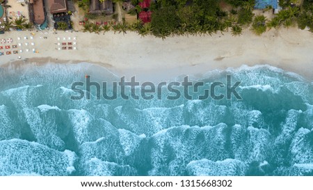 Aerial : Overhead  of people enjoying the summer at sand  beach resort line ,waves breaking against the coast 