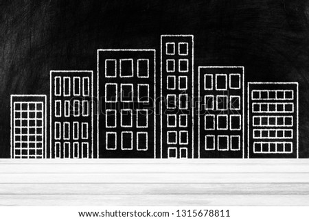 White Wood Table with Buildings Drawing on Chalkboard Background, Suitable for Product Display.