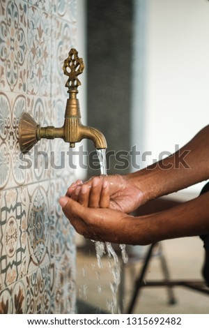 Ablution flow before perform a prayer in a mosque by using classic pipe. Image may soft and contains grain due to photo effect and vintage lens quality. Royalty-Free Stock Photo #1315692482