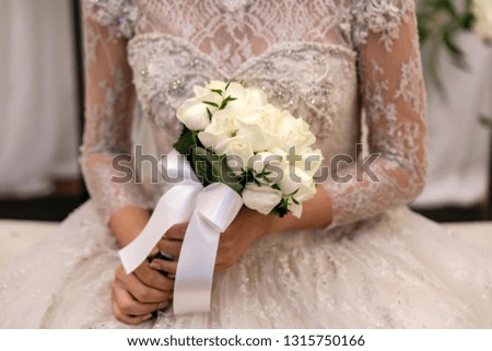 Bride holds a wedding bouquet. Very nice young woman in a white wedding dress holding a beautiful blossoming flower bouquet of various kinds of fresh real flowers, in pink, red and pastel cream colors
