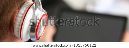 Male wearing headphones wired to pc pad in arms at home closeup. Stock market trade and investment interactive data search wifi connection wireless ip telephony inspiration idea web social network
