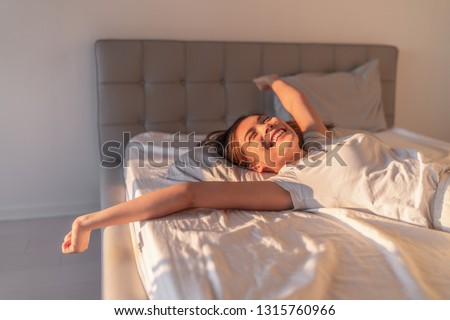 Happy woman lying in comfortable foam latex mattress bed in luxury hotel enjoying relax weekend getaway jumping in bed. Enjoying Asian woman with open arms in freedom. Royalty-Free Stock Photo #1315760966