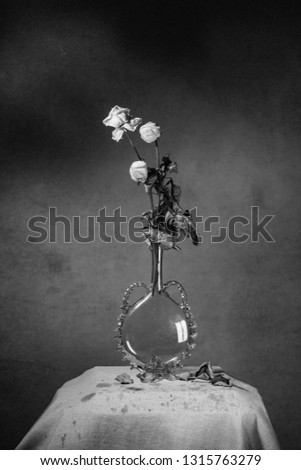A bouquet of three white roses in a vase, standing on the table.
