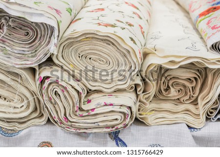 Rolls of natural fabrics and textiles  lie at a market stand. Sewing industry concept