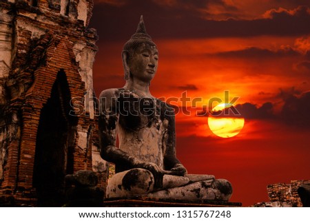 The Big Oldest statue of Buddha in Ancient temple, Autthaya,Thailand with dark cloud and sun sky background