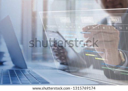 Project management. Project manager updating tasks, milestone progress planning with augmented reality Gantt chart scheduling on virtual screen. Businessman working on digital tablet, laptop computer