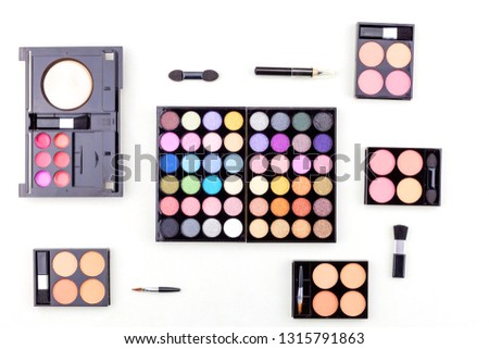 Flat lay photo of various makeup brush, eyeshadow and cosmetics on white background