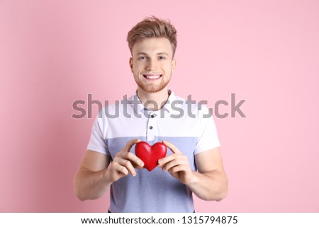 Portrait of young man with decorative heart on color background