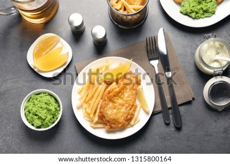 Plate with British traditional fish and potato chips on grey table, top view