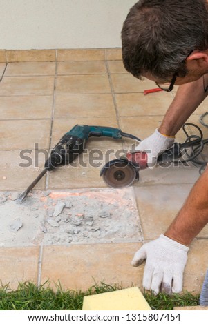 A circular saw. A man sawing ceramic tiles. Worker sawing a tile on a circular saw. Construction works. Tiling Workshop