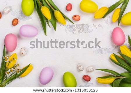 Easter background with yellow spring tulips, colorful eggs and chocolate candy eggs. Copy space