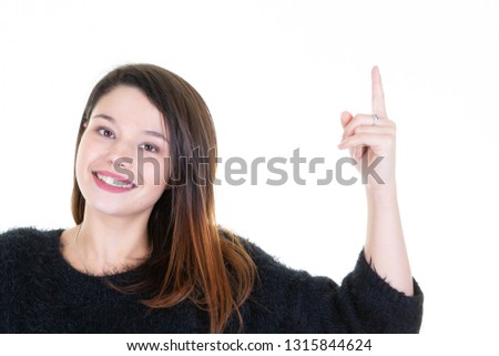 Cheerful lovely young woman standing and pointing away