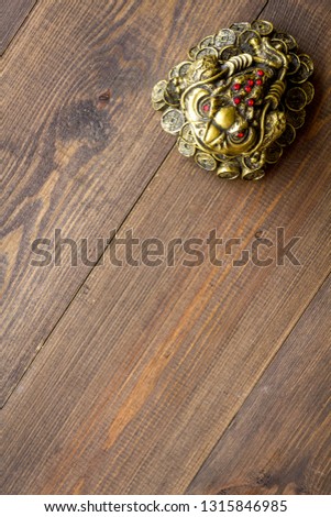 Buddhist symbol. Oriental three legged toad with gold coins on dark wooden background top view copy space