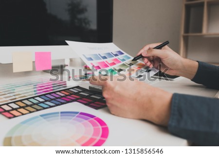 Hand designer choosing colors for doing graphic on laptop.