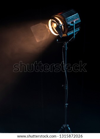 Beautiful studio light for a movie and TV show on a dark background with smoke. A ray of light penetrates the smoke and darkness. Professional light for the production of cinema.