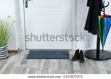 Hallway interior with mat and clothes stand near door Royalty-Free Stock Photo #1315872371